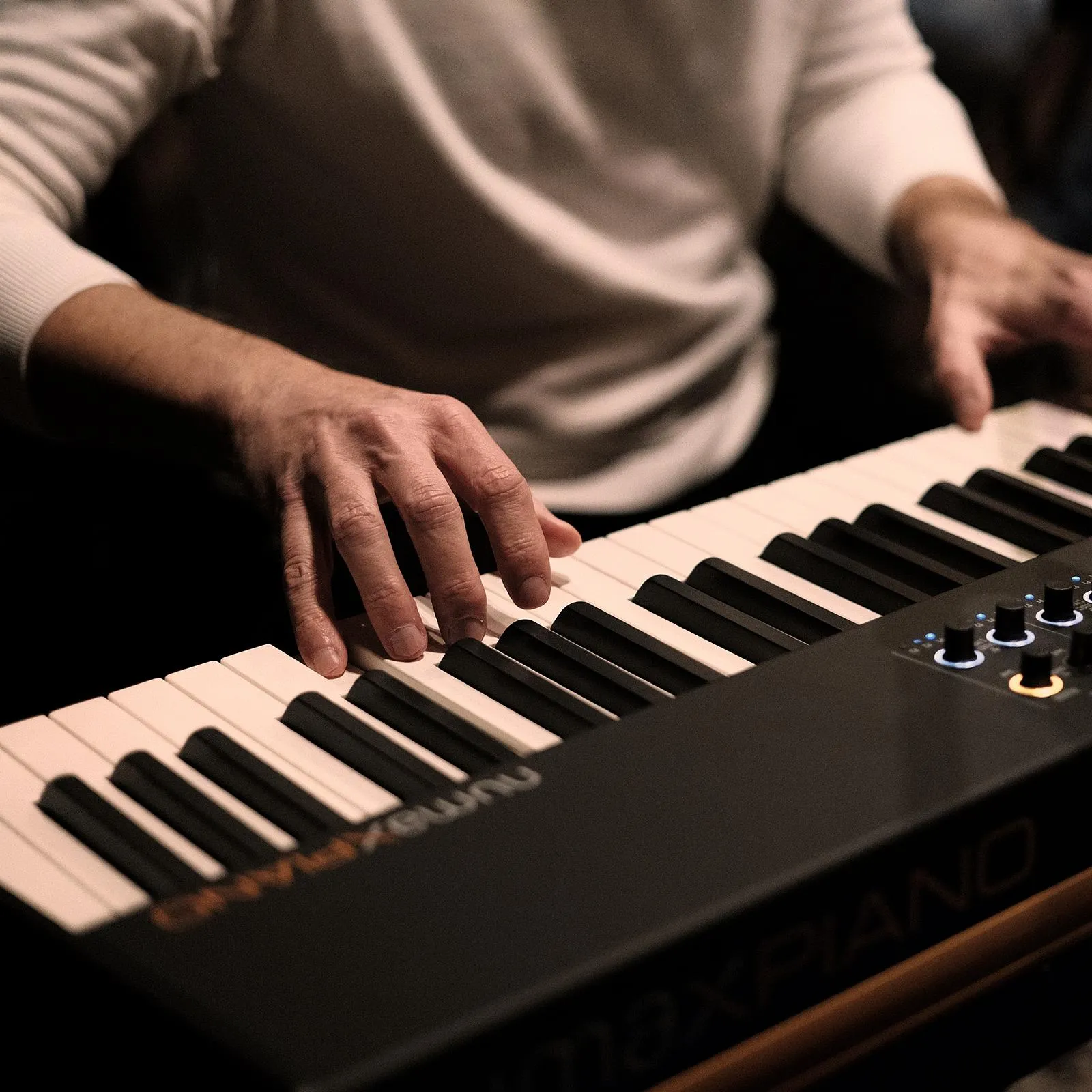 Close-up of hands playing a stage piano