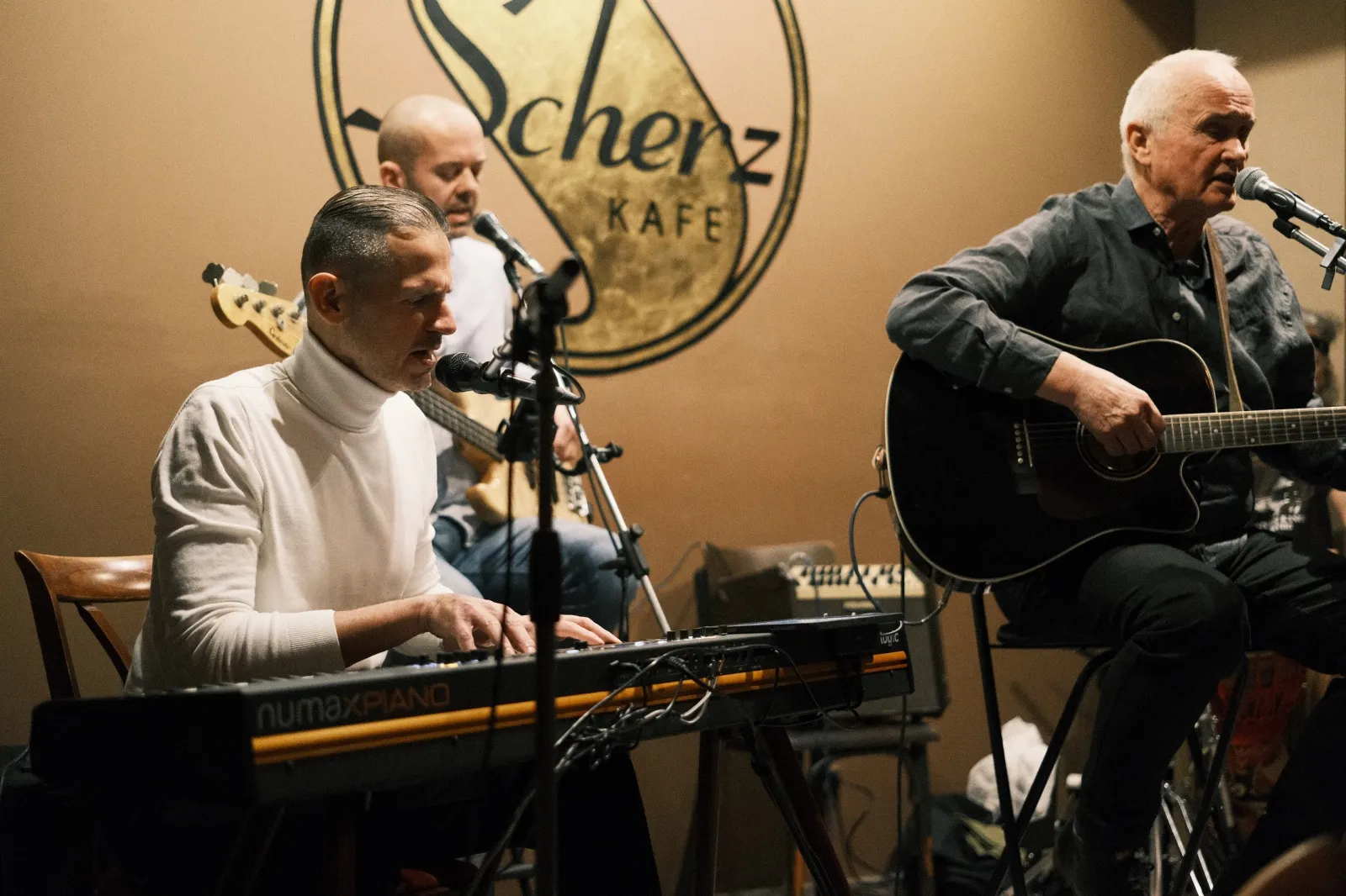 Milan Vodrážka playing stage piano outdoors with IC Band, percussion and bass guitar in background